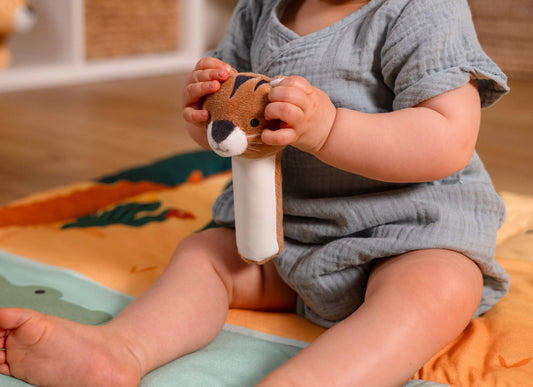Baby holding a plush toy on a colourful play mat