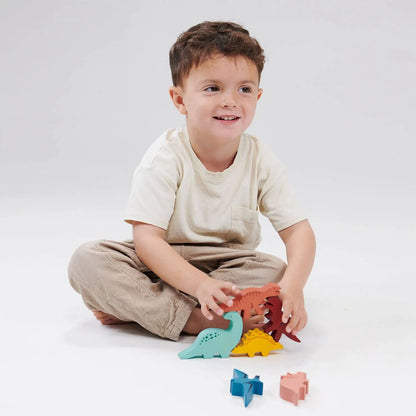 Child playing with colourful dinosaur toys on a white background