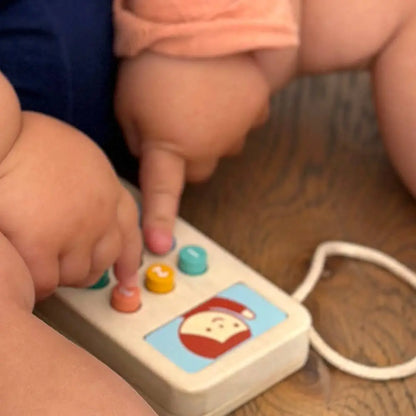 Child's hands interacting with a colourful toy phone on a wooden floor