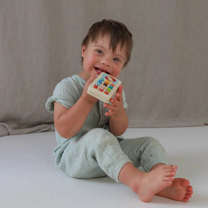 Child holding a colourful toy phone against a neutral background.