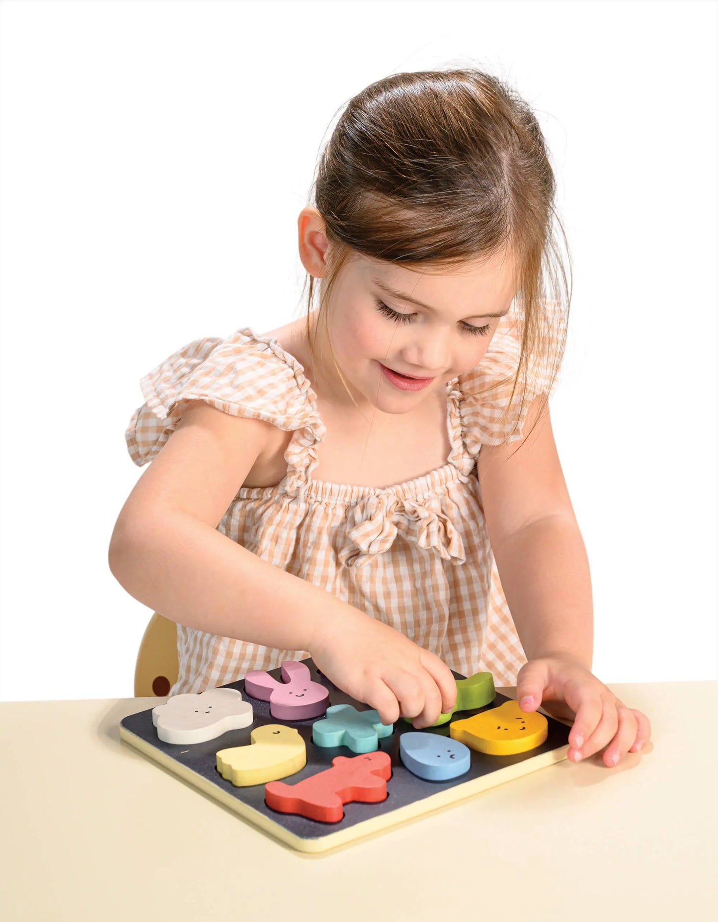 Young girl playing with a wooden puzzle on a white background