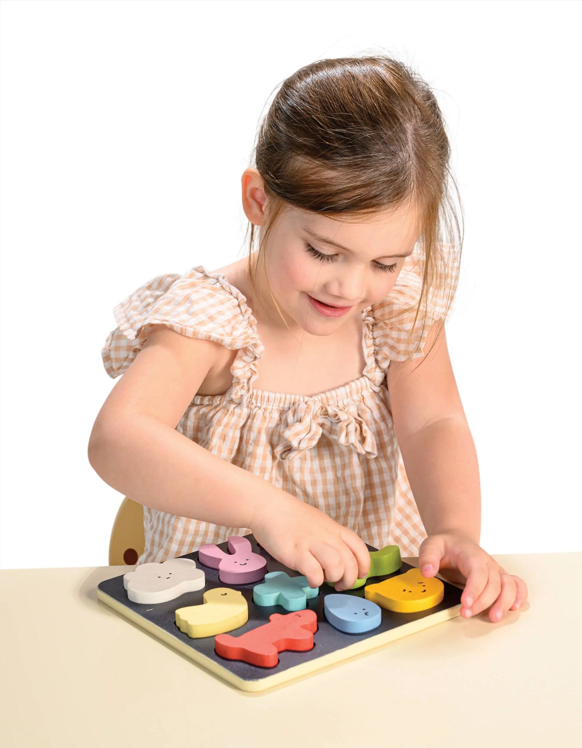 Young girl playing with a wooden puzzle on a white background
