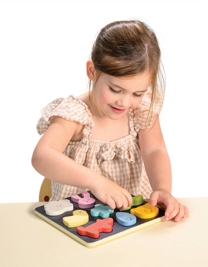 Young girl playing with a wooden puzzle on a white background