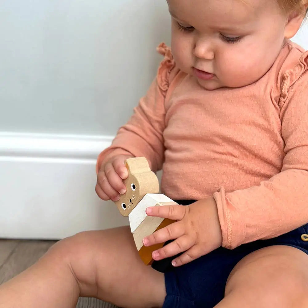 Child playing with a wooden toy shaped like a cat