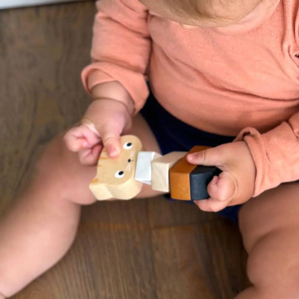 Child holding wooden kitten toy on a wooden floor