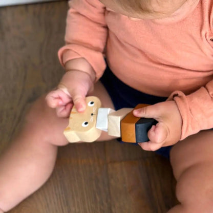 Child holding wooden kitten toy on a wooden floor