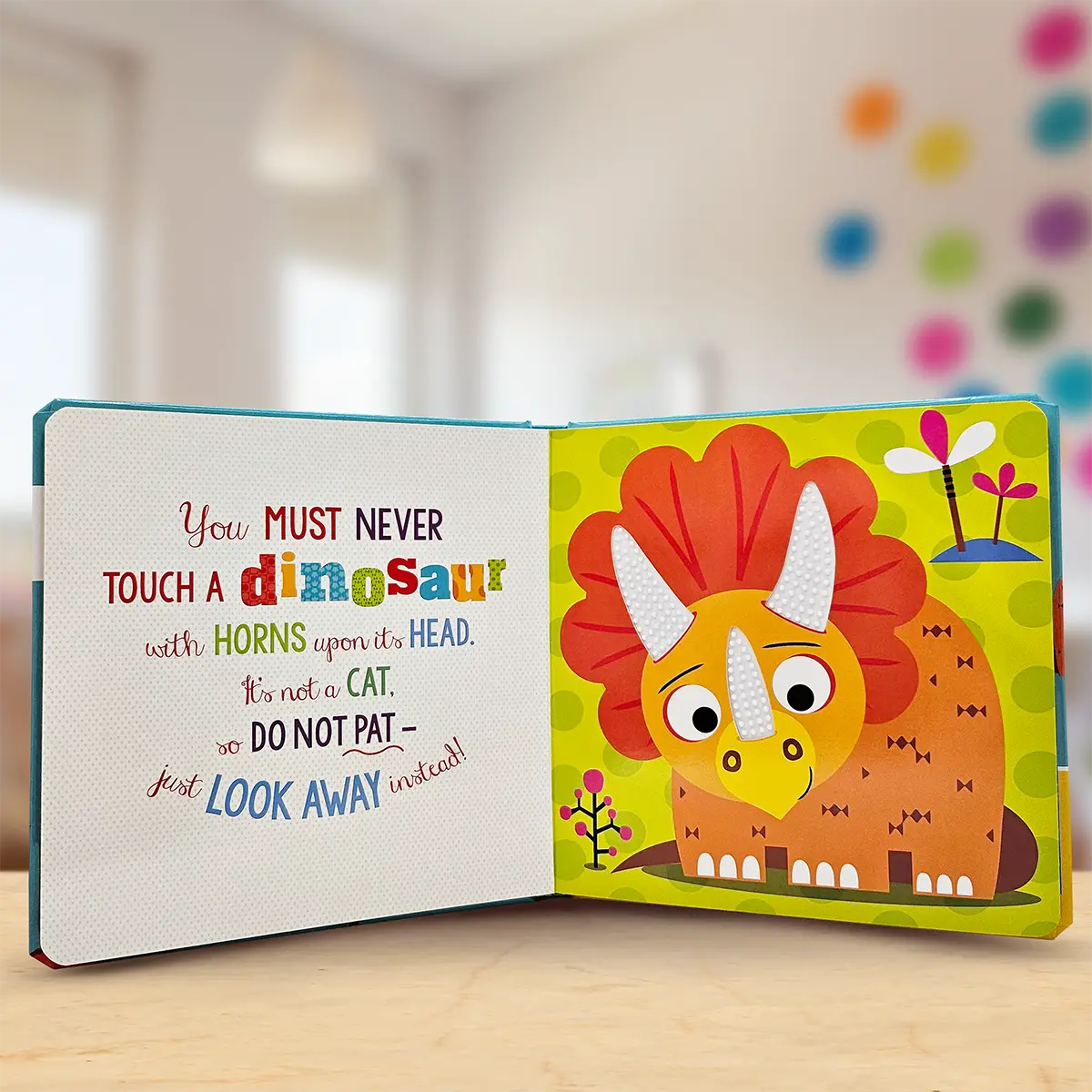 Children's book with a colourful dinosaur illustration and text on a wooden surface.