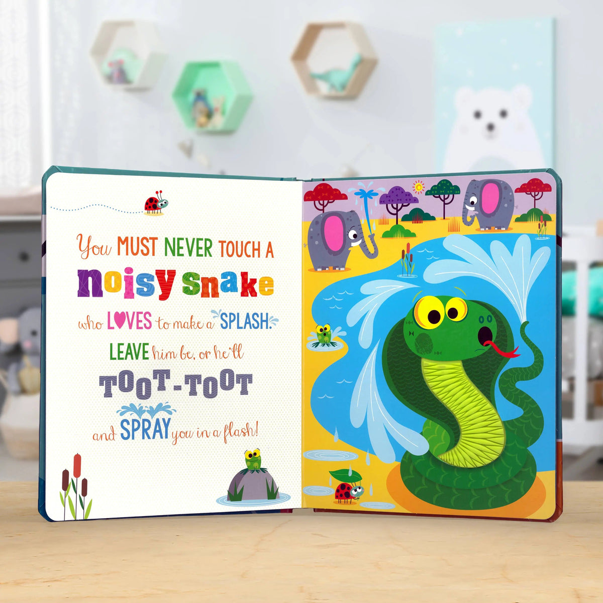 Open children's book with a colourful snake illustration and text on a wooden surface.