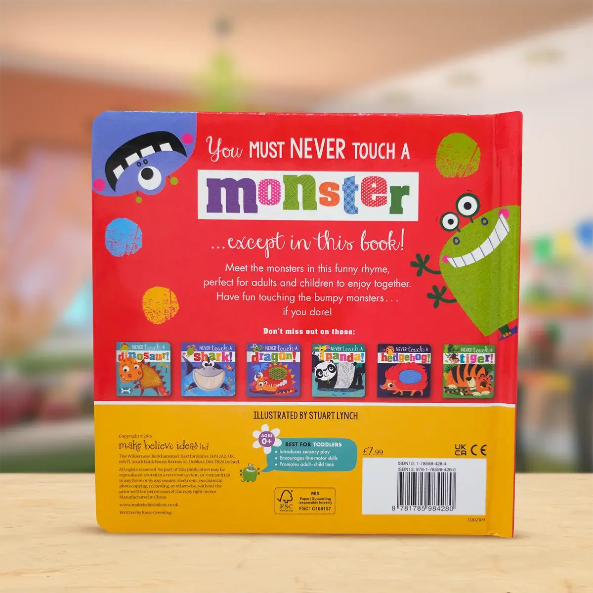 Back cover of a children's book titled 'You Must Never Touch a Monster' with colourful illustrations on a wooden surface.