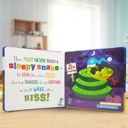 Children's book open to a page with a green snake illustration and text on a wooden surface.