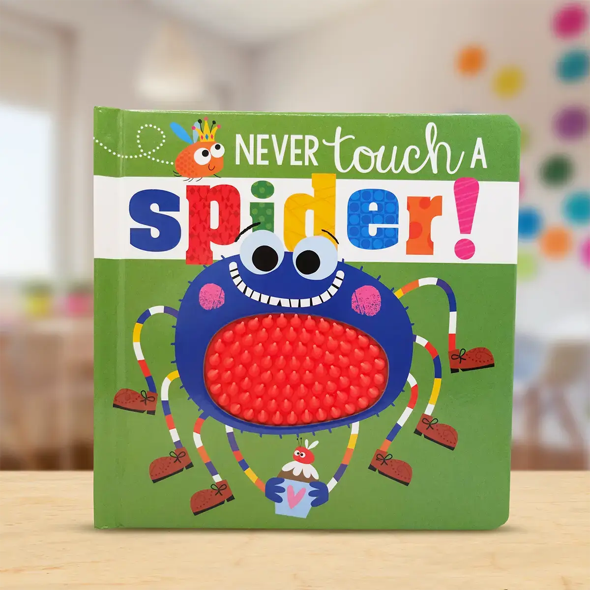 Children's book titled 'Never Touch a Spider!' with colourful spider illustration on a wooden surface.
