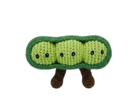 Crocheted green pea pod with small black eyes and brown legs on a white background