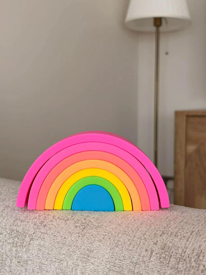 Colourful silicone  rainbow toy on a textured surface with a neutral background