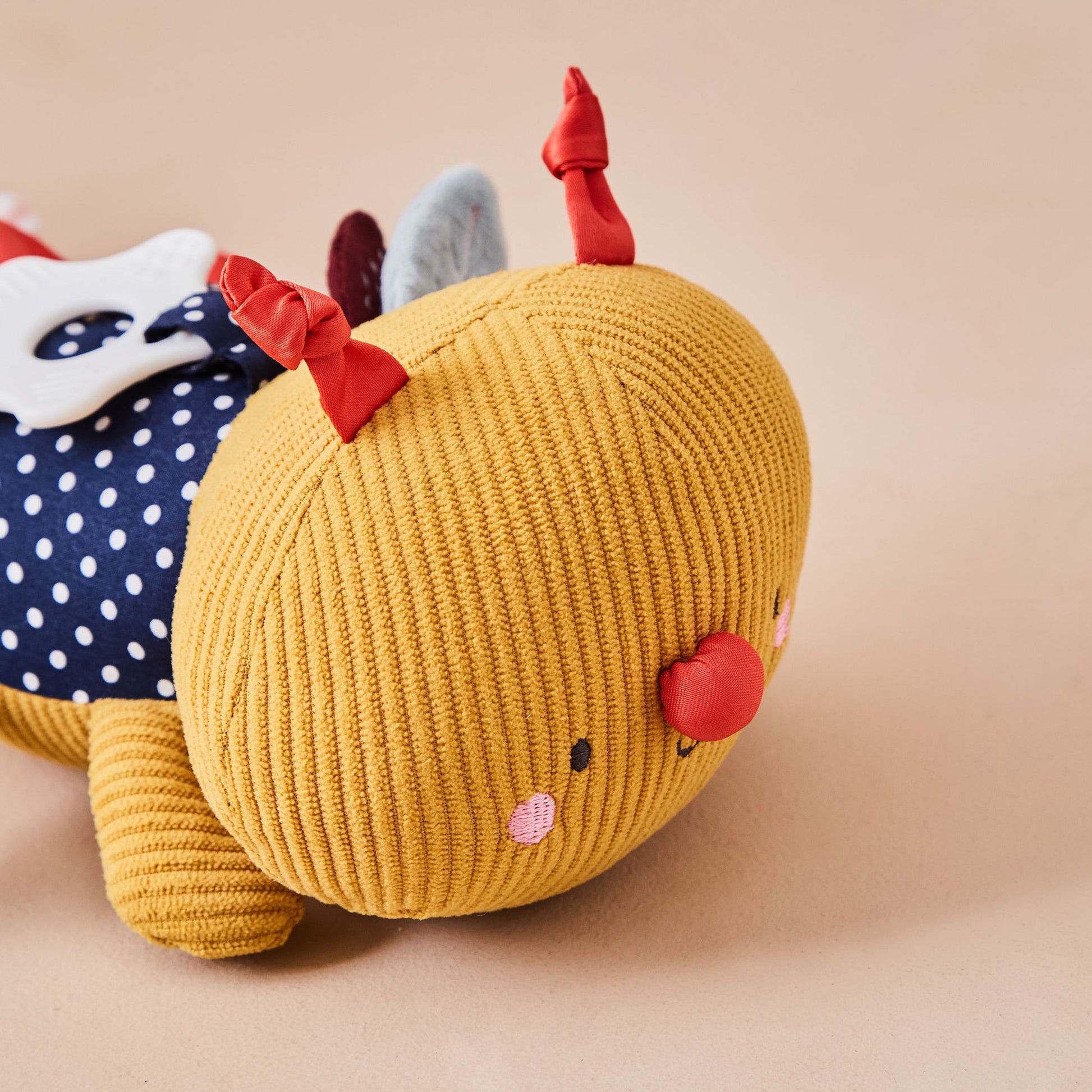 Yellow plush toy with red accents on a beige background