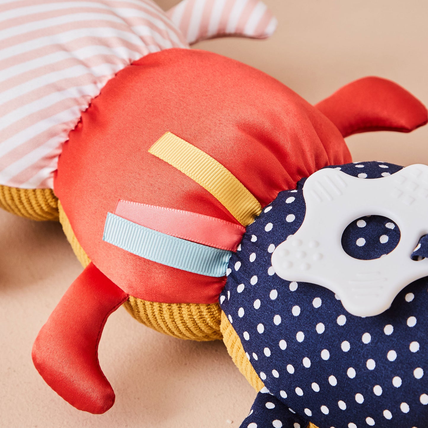 Close-up of a soft toy with colourful textures and patterns on a beige background