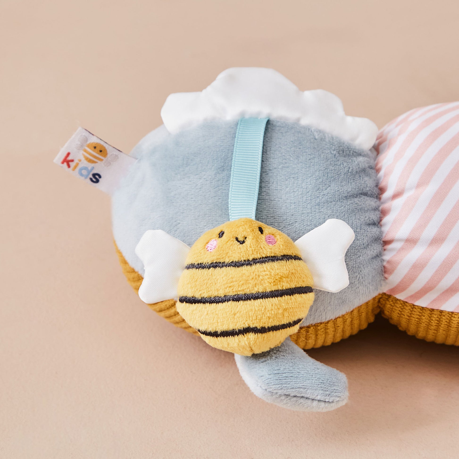 Plush caterpillar toy with a bee design on a beige background