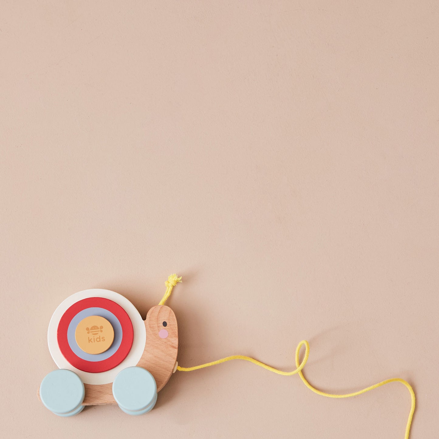 Wooden toy snail with colourful shell on a beige background