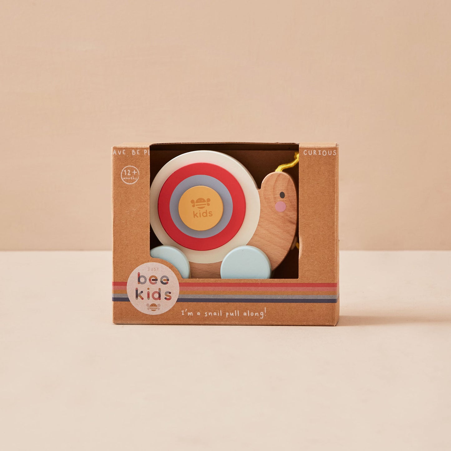 Children's snail toy in a brown box with 'just bee kids' branding on a beige background