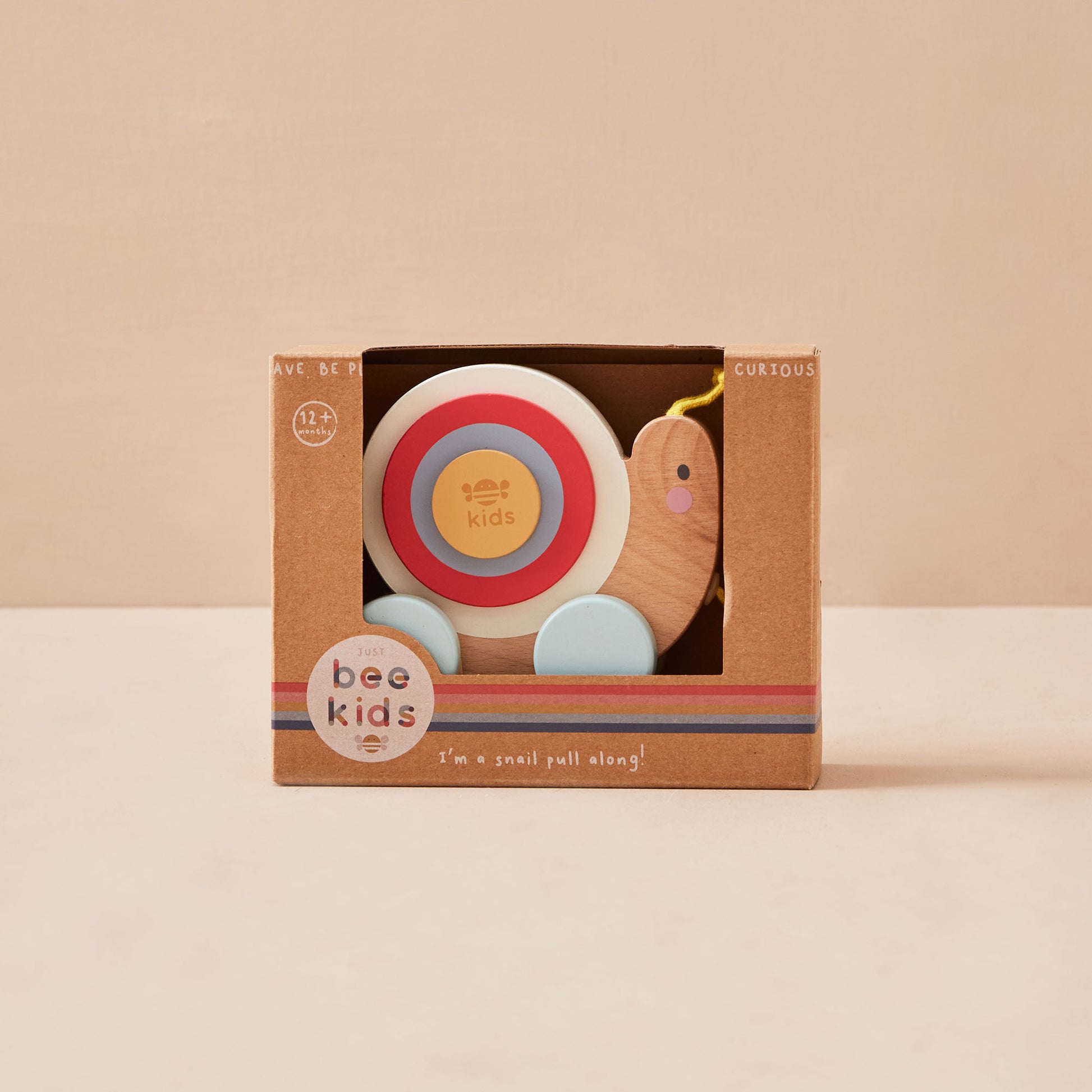 Children's snail toy in a brown box with 'just bee kids' branding on a beige background