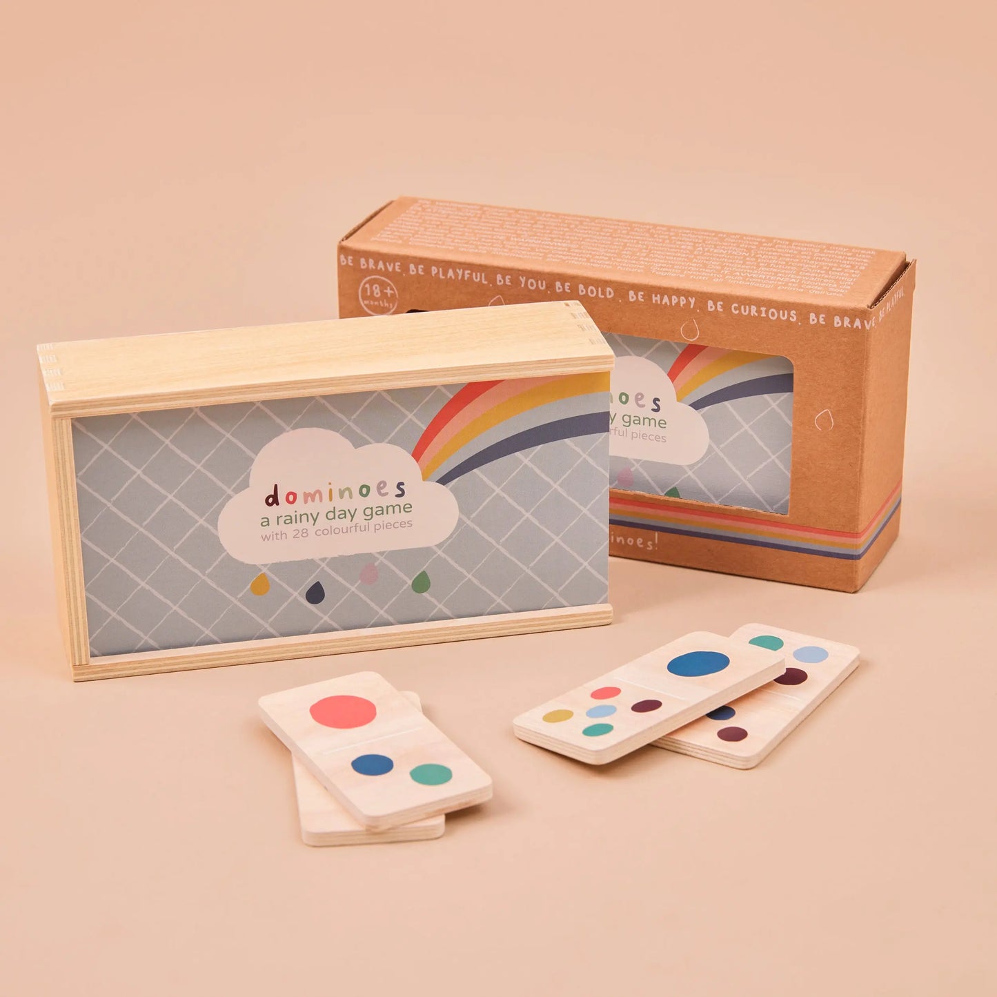Set of dominoes with colourful dots on a beige surface, featuring a matching cardboard box.