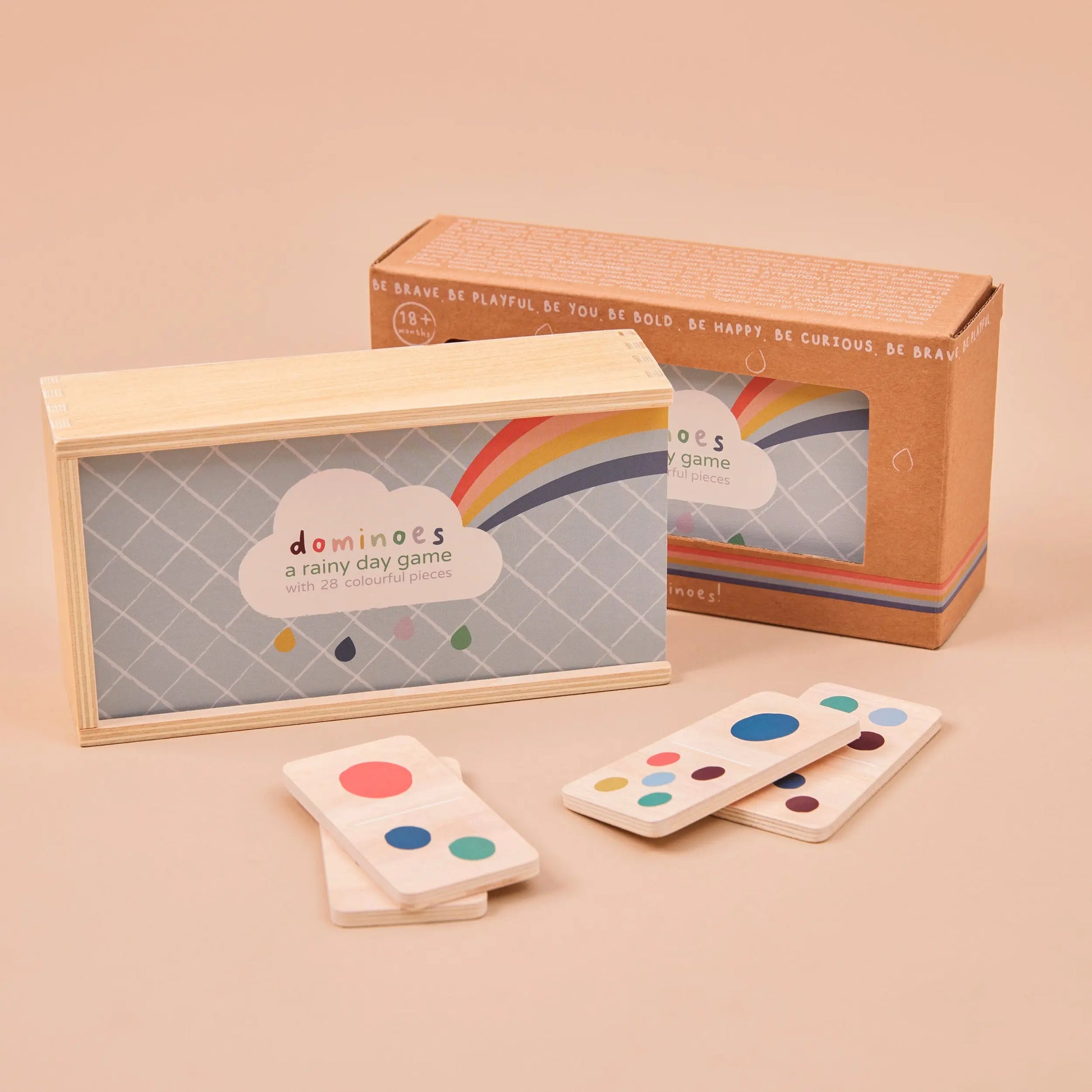 Set of dominoes with colourful dots on a beige surface, featuring a matching cardboard box.