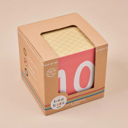 Cardboard box with a pink box featuring the number '10' and 'just bee kids' branding on a beige background.