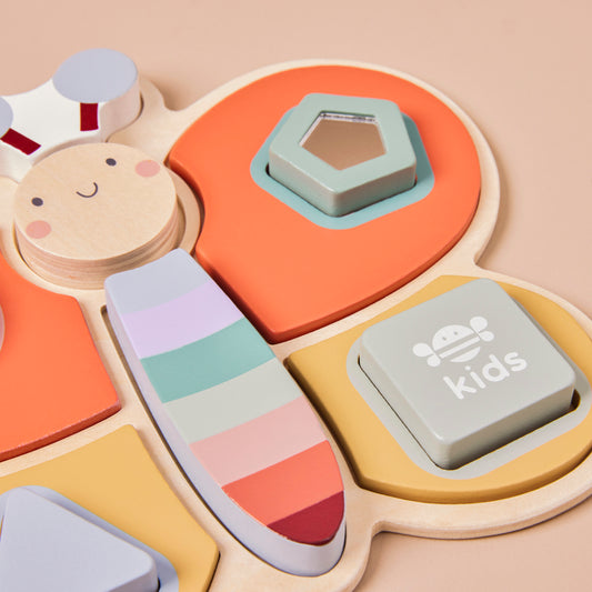 Colourful children's dragonfly puzzle toy with geometric shapes on a beige background