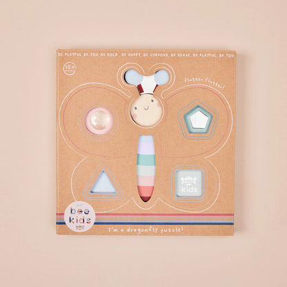 Dragonfly-shaped puzzle packaging with colourful dragonfly figure on a beige background