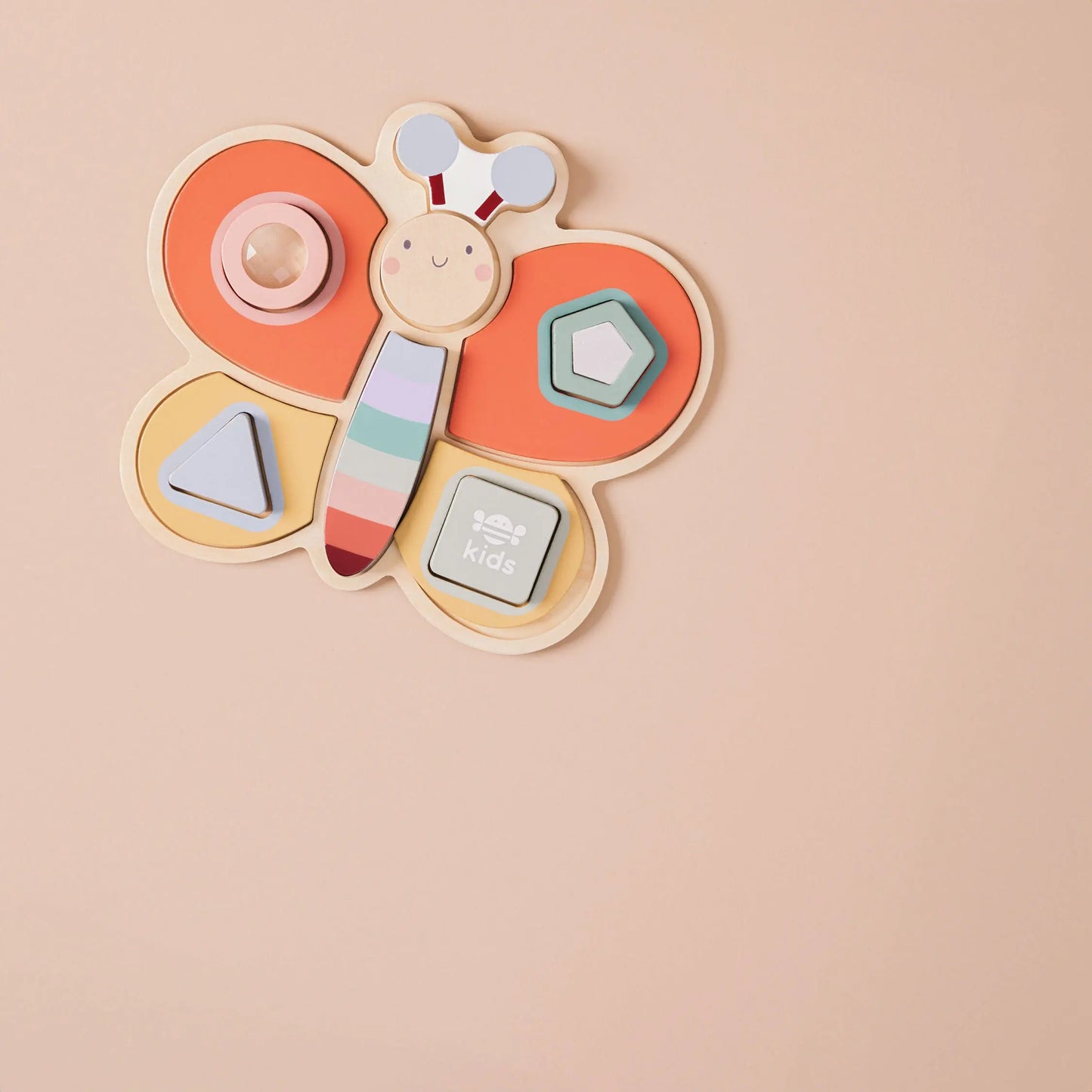 Dragonfly-shaped wooden toy with colourful geometric pieces on a beige background