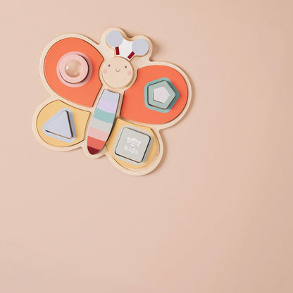 Dragonfly-shaped wooden toy with colourful geometric pieces on a beige background