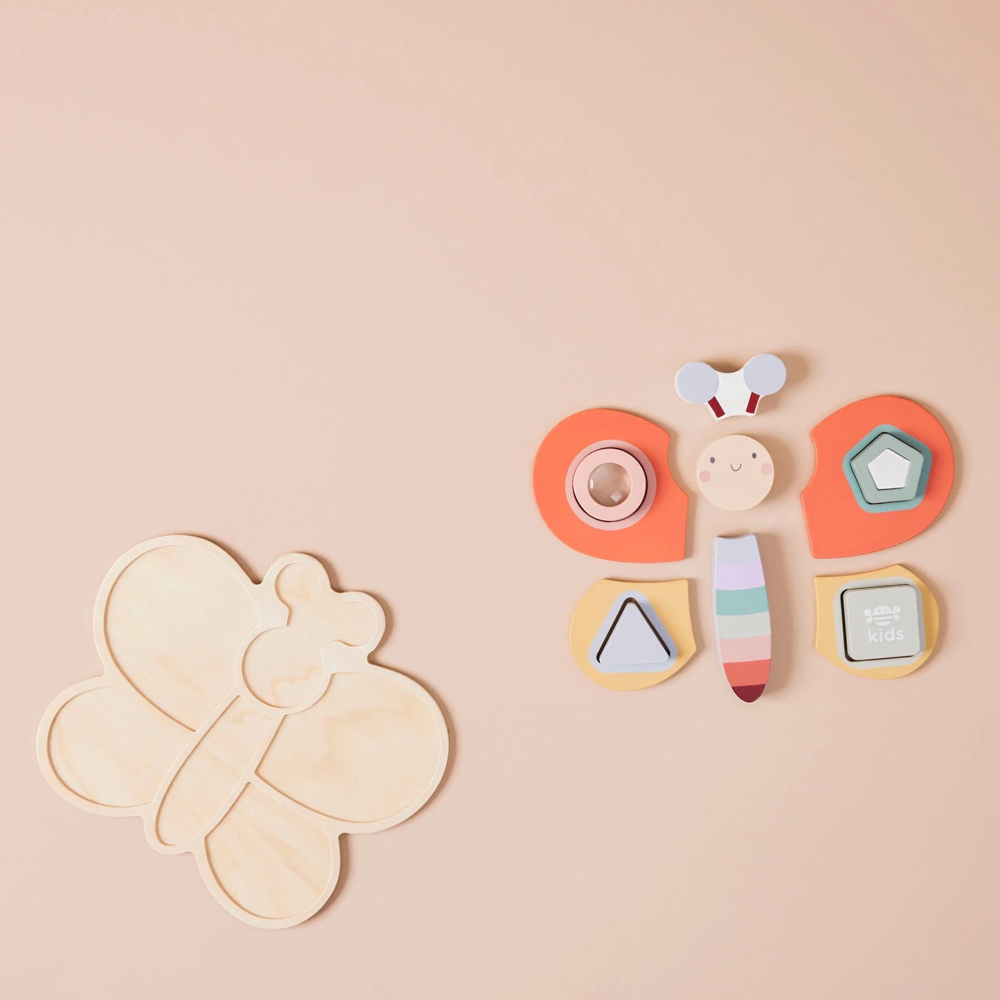 Dragonfly-shaped wooden toy with colourful elements on a beige background