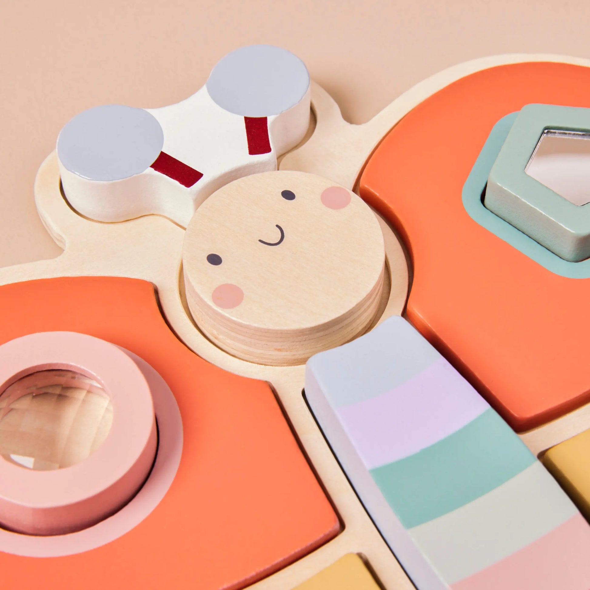 Colourful wooden dragonfly toy with geometric shapes on a beige background