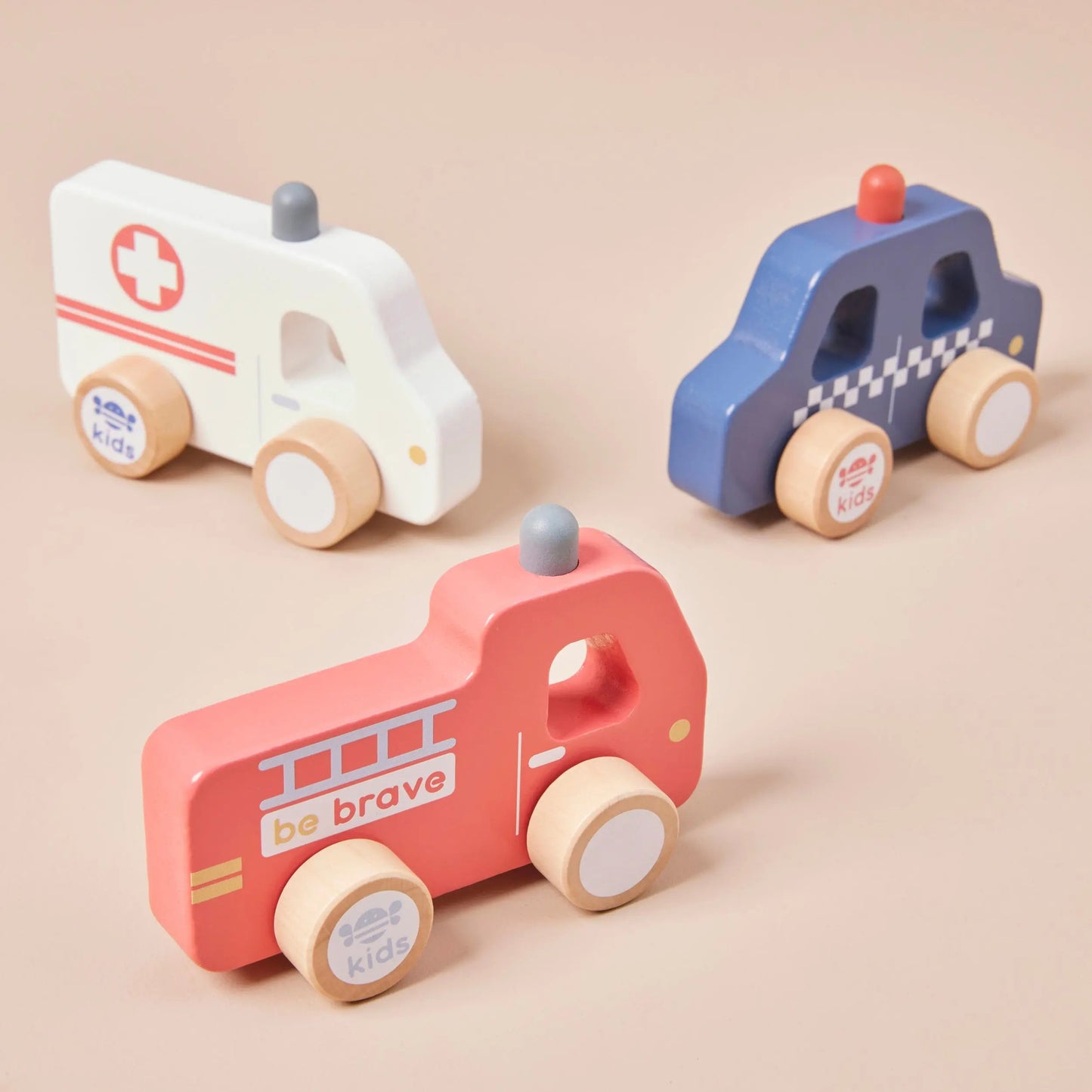 Three wooden toy emergency vehicles on a beige background