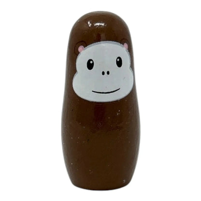 Brown wooden monkey toy with a white face featuring black eyes and a smile on a white background