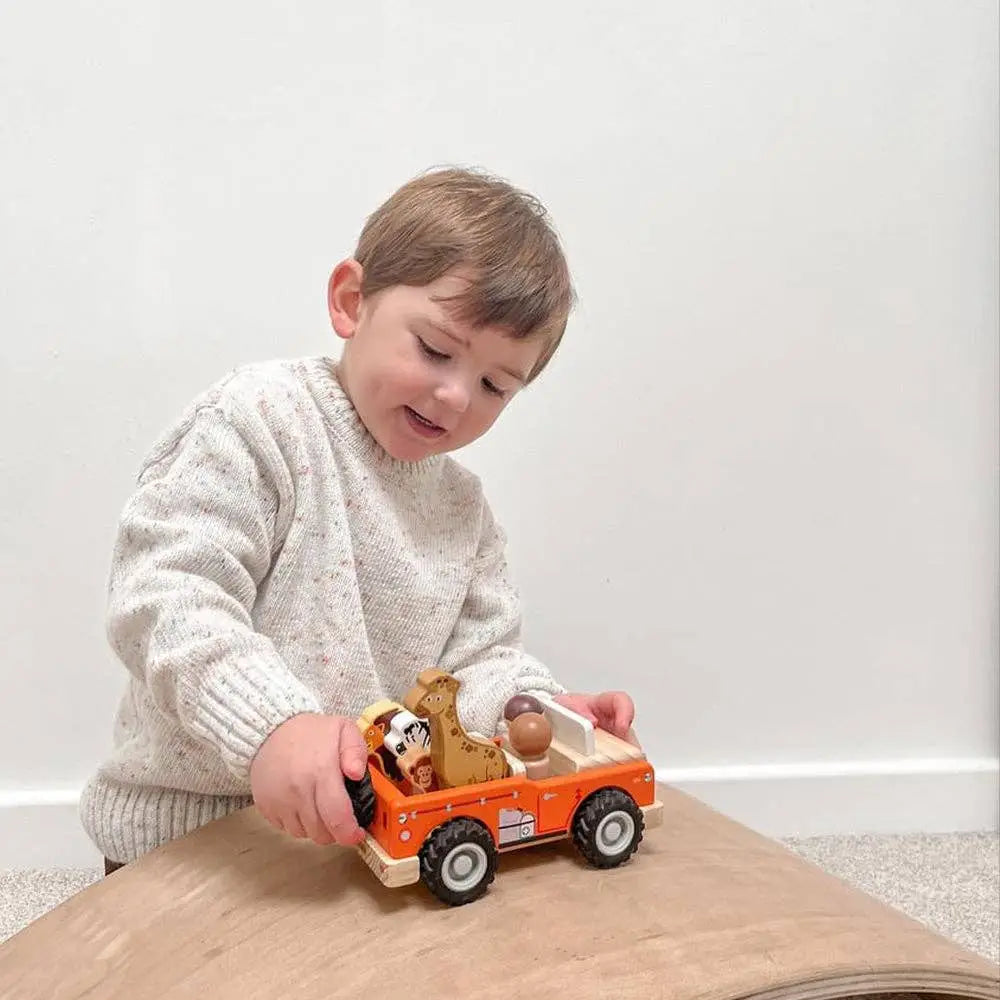 Child playing with a toy truck on a wooden surface