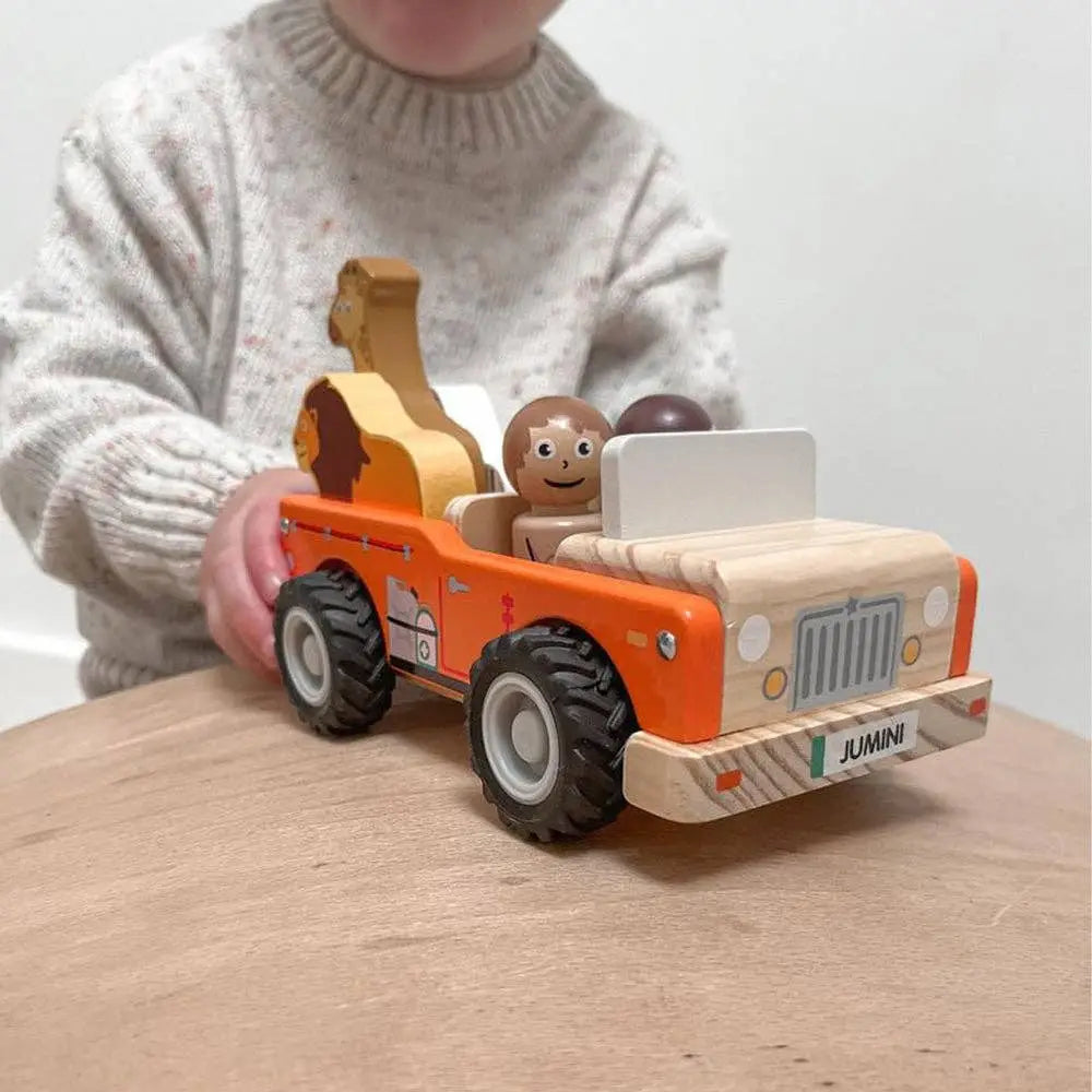 Child playing with a wooden toy truck on a wooden surface