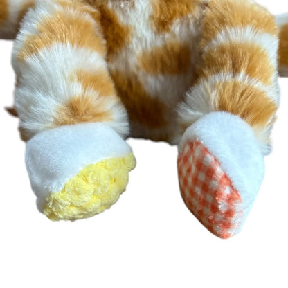 Close-up of a plush toy's front paws and feet, featuring orange and white striped fluffy fur, white padded paw cuffs, one yellow-padded paw cuff, and an orange-and-white checkered paw pad.