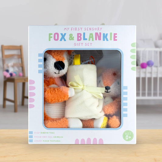 Fox and blanket gift set in packaging with a baby crib and chair in the background