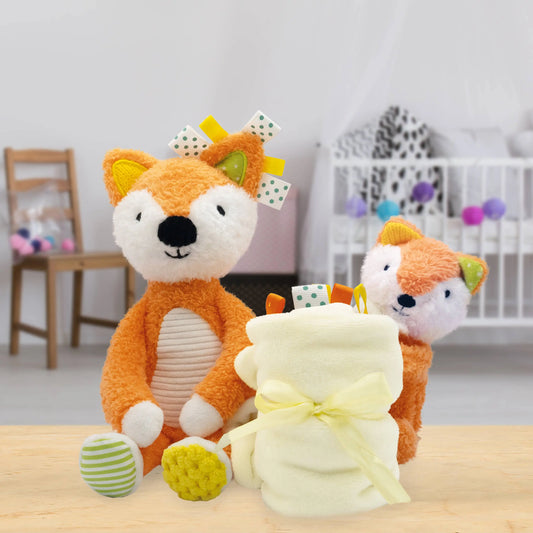 Two fox plush toys with a yellow blanket on a wooden surface in a room setting.