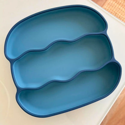 A three-compartment silicone baby feeding tray in a solid medium blue color, shown from an overhead angle on a white surface.