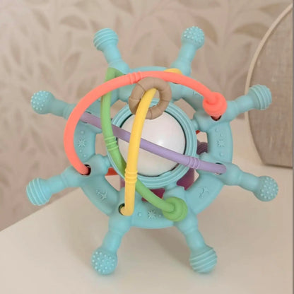 A baby sensory toy with a light blue star-shaped frame, textured rubber spikes, a white ball in the center, and colorful wavy tubes in orange, yellow, green, purple, and beige.