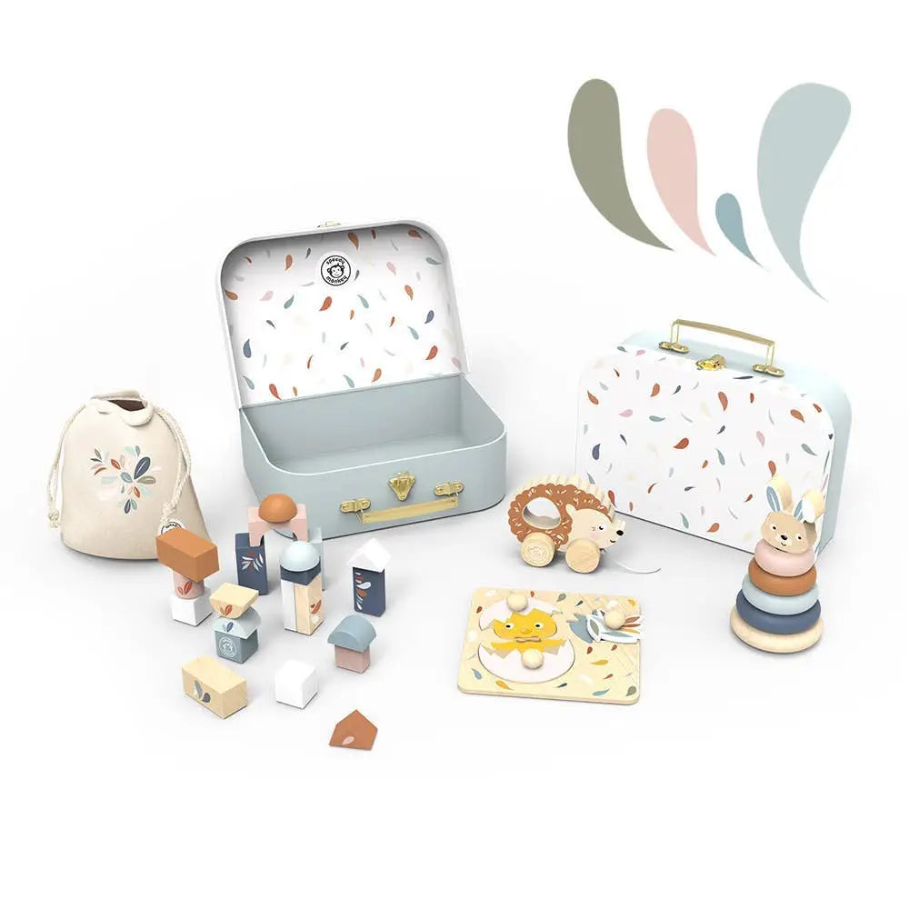 Collection of wooden toys including blocks and a rabbit figure, displayed with a colourful suitcase and small bag on a white background.