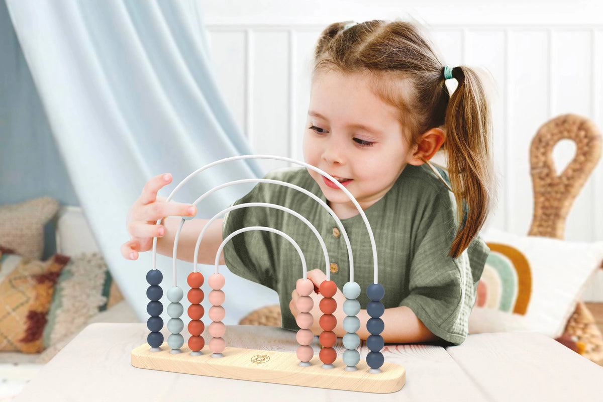 Child playing with a colourful abacus indoors