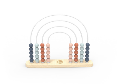 A wooden arch bead toy with six vertical columns of round beads in muted blue, pale green, terracotta, peach, and light grey, suspended over a light natural wood base with a small gold circular logo in the centre.
