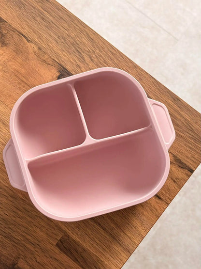 Pink divided bowl on a wooden surface