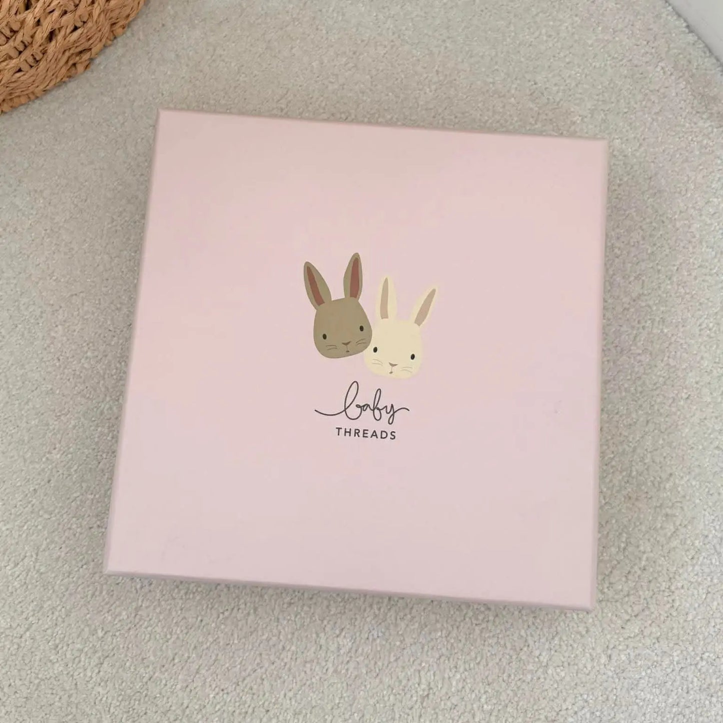 Pink box with cartoon bunnies on a light gray surface