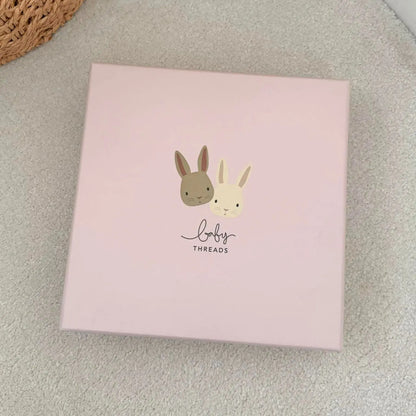 Pink box with cartoon bunnies on a light gray surface