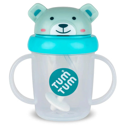 A clear plastic baby tumbler with two handles, a turquoise lid, and a mint green bear-shaped top. The cup features a teal circular sticker on the front with the brand name 'TUM TUM'.