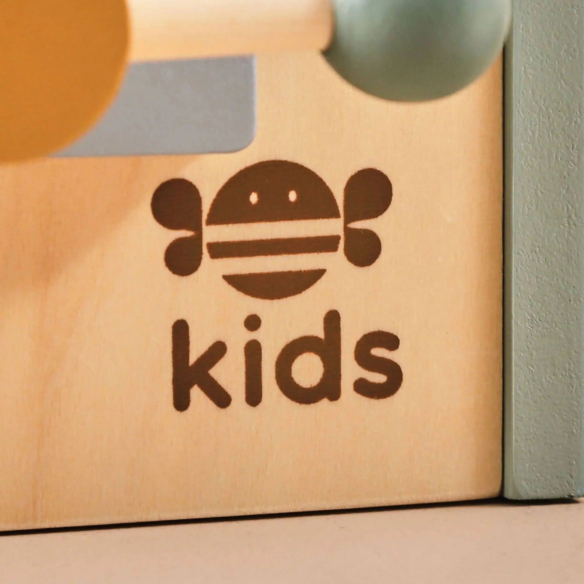 Wooden toy box with 'just bee kids' logo on a neutral background