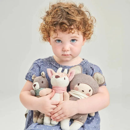 Child holding three plush toys against a plain background